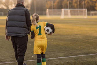 Barn bliver fulgt til fodbold af en voksen